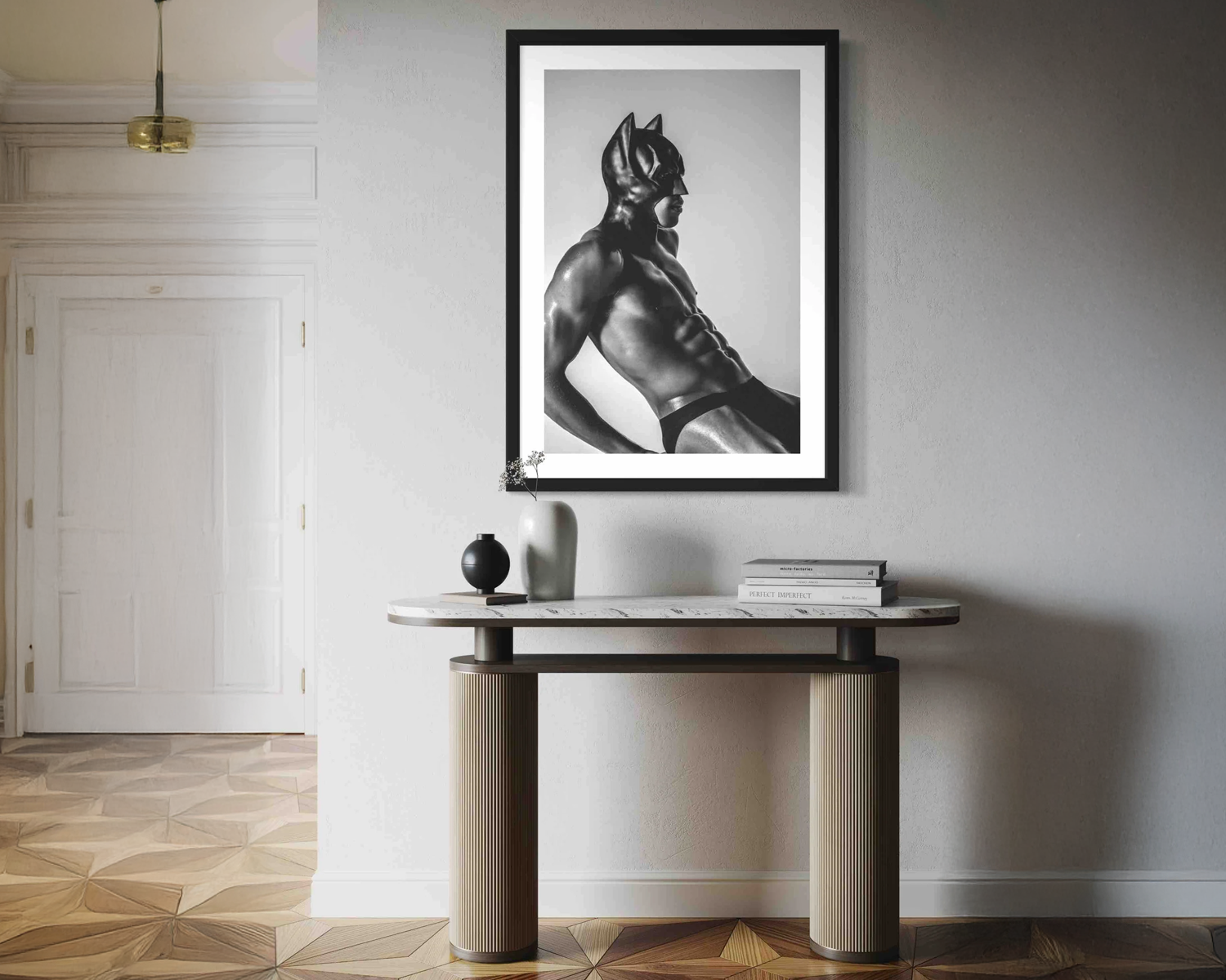 Framed black and white art print of a muscular figure on a wall above a console table.