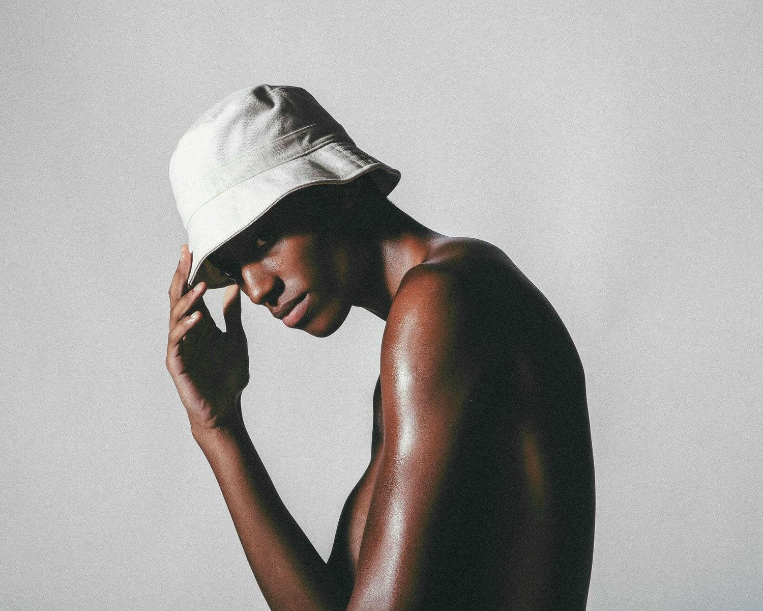 Person wearing a white bucket hat against a plain background