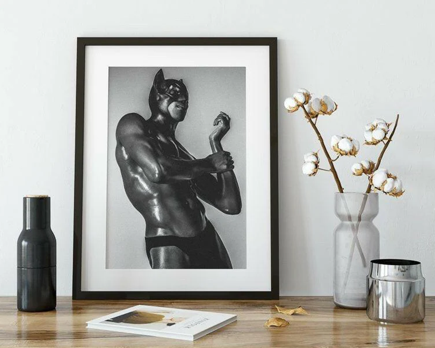 Framed black and white superhero print on a wooden surface with decorative items.