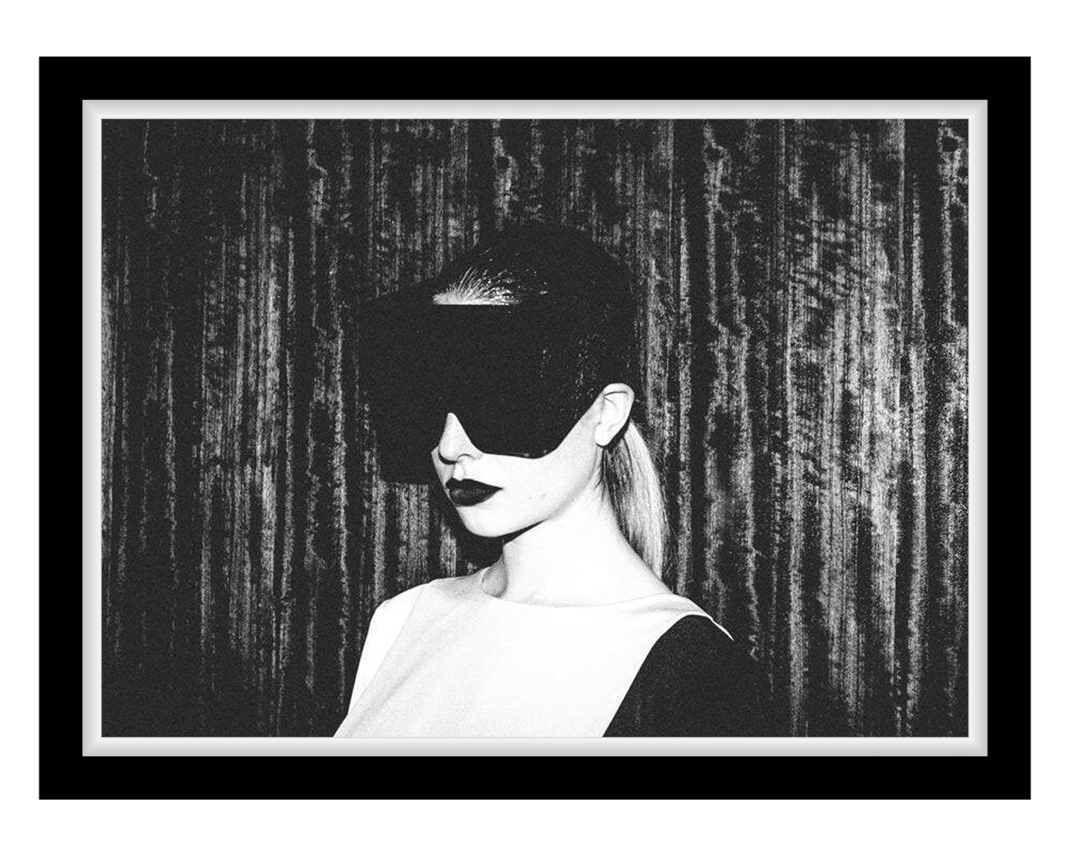 A monochrome image of a figure wearing a futuristic visor, posing against a textured dark background. The atmosphere is mysterious and artistic.