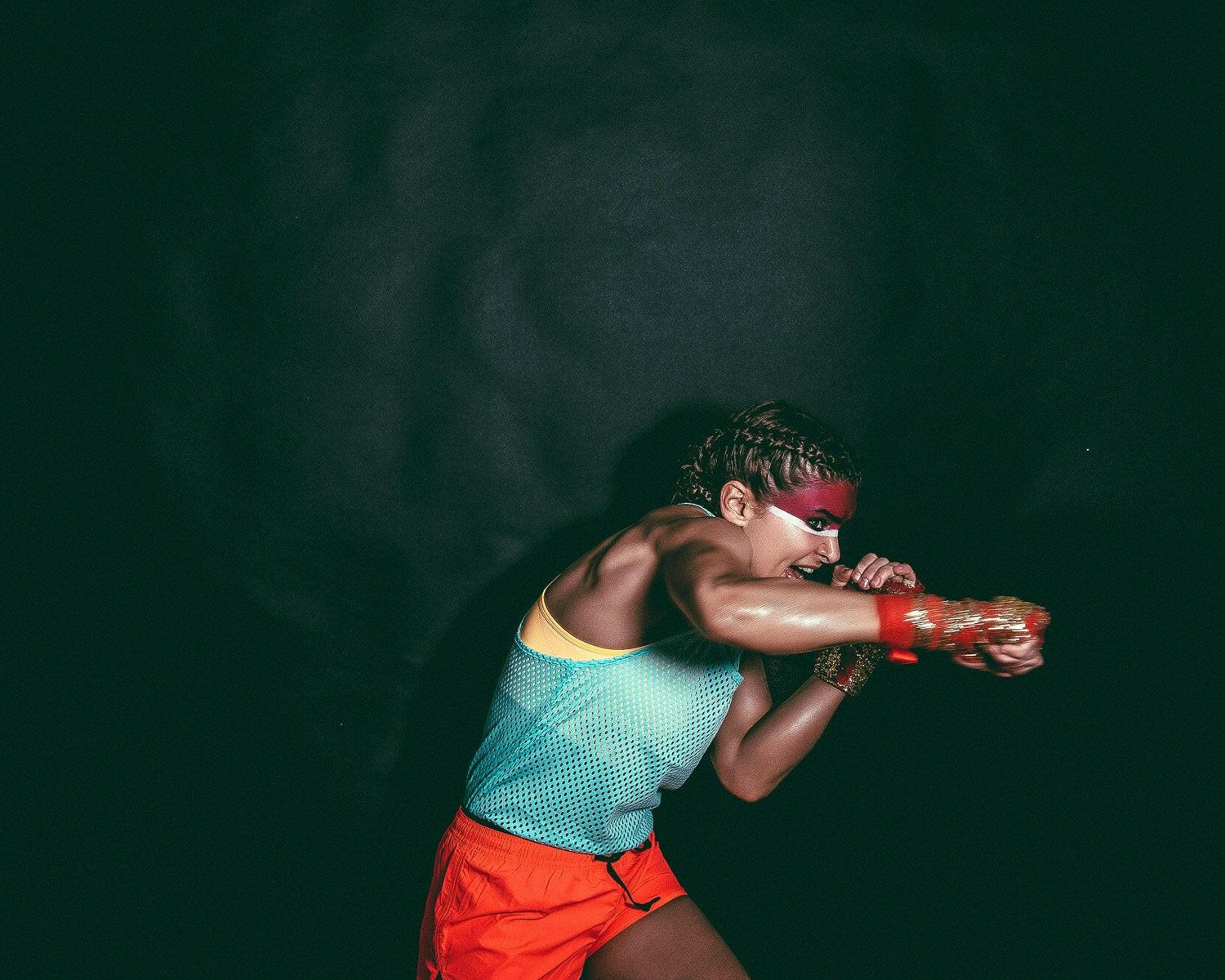 Girl in athletic wear with red boxing gloves on a dark background