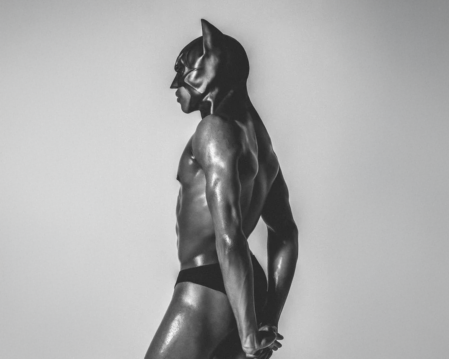 Black and white statue of a muscular figure in a dynamic pose against a plain background