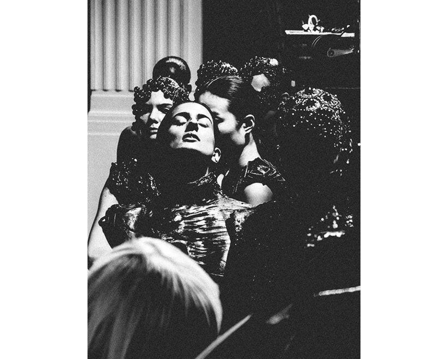 Black and white photograph of a woman in a glamorous setting with other people.