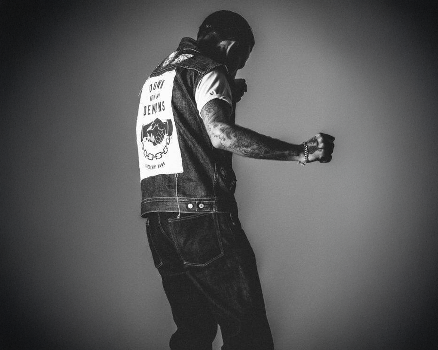 Person wearing a denim jacket with branding on the back against a plain background