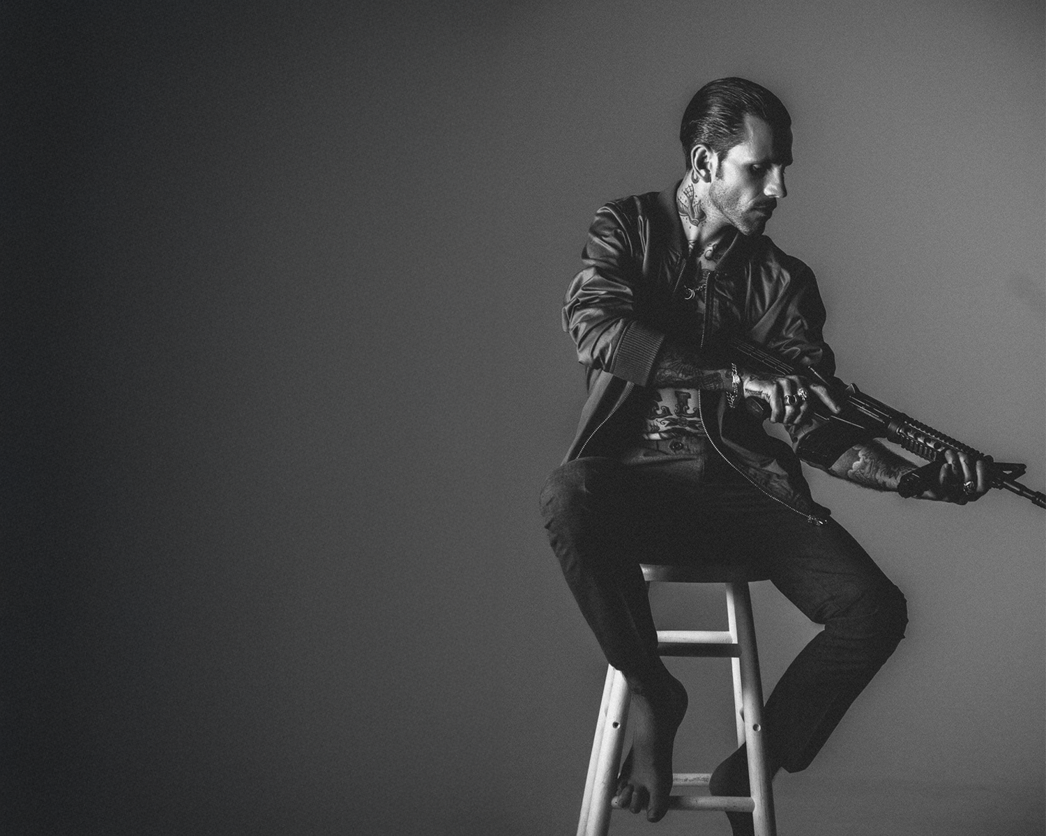 Man sitting on a stool against a plain background