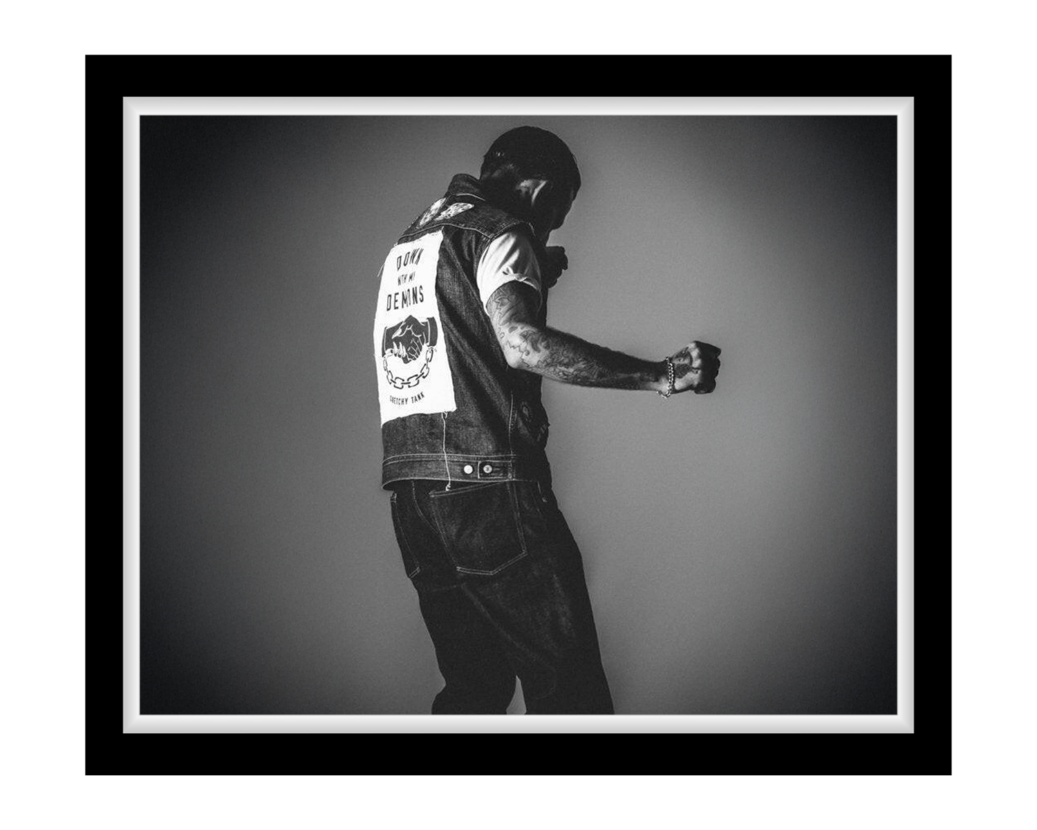 Person wearing a vest with text and graphics, standing against a plain background