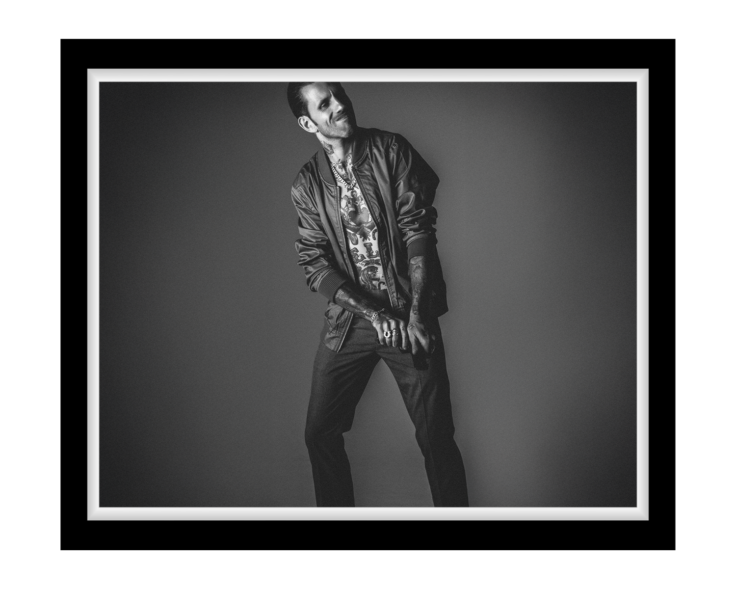 Black and white portrait of a person wearing a jacket and pants against a plain background