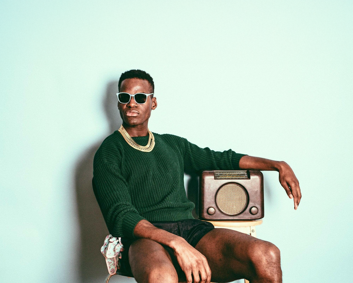 Man sitting on a vintage radio with a light blue background