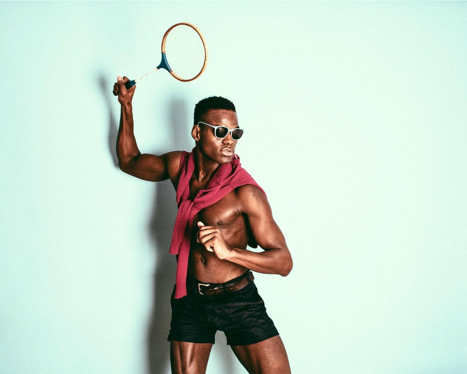 Man holding a badminton racket against a light blue background