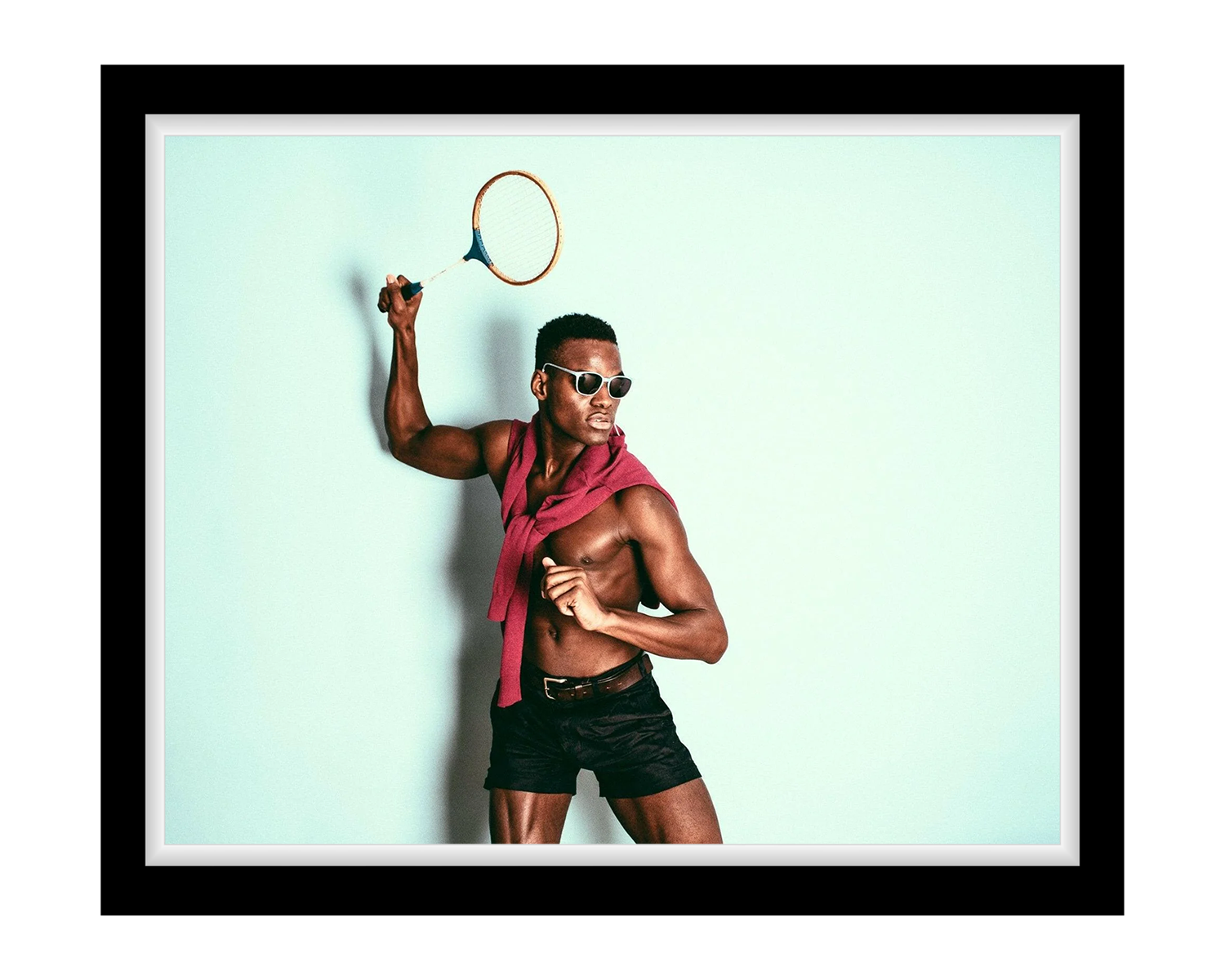 Man holding a badminton racket with a light blue background