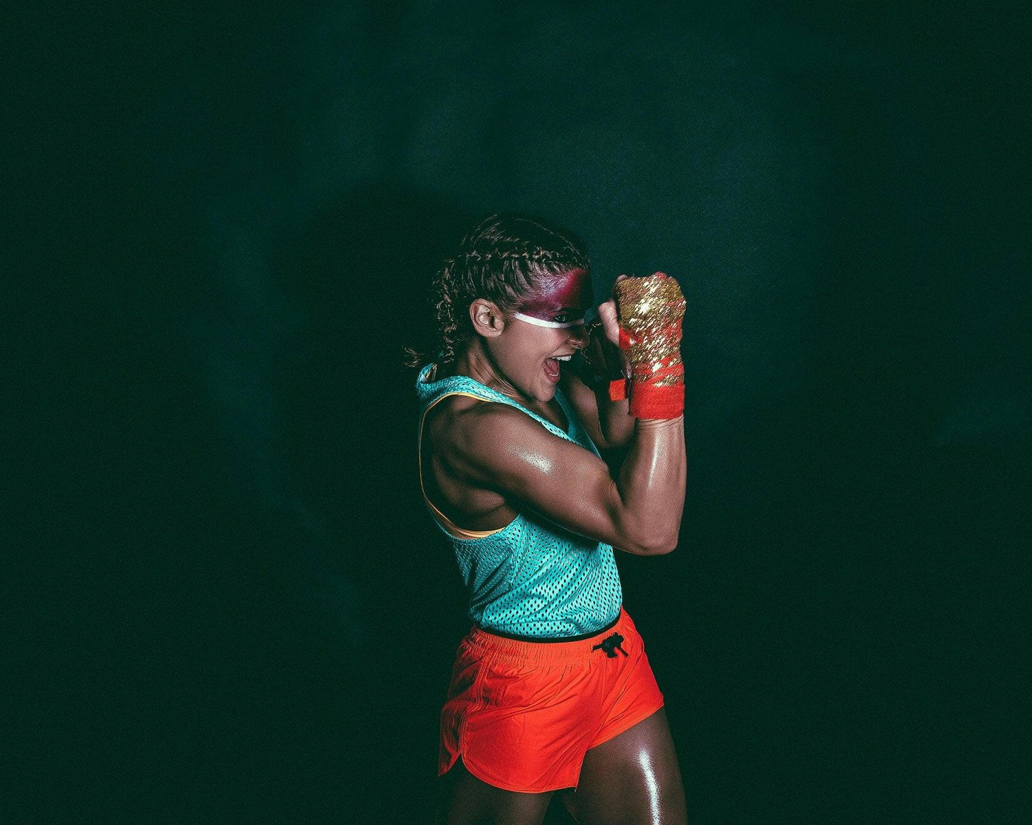 Person in athletic wear with red boxing gloves against a dark background